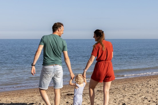 Familie aan het wandelen over het schone zandstrand in Schouwen-Duiveland