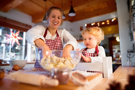 Mutter und Kind backen Kekse während der Dezemberferien in einer Ferienwohnung