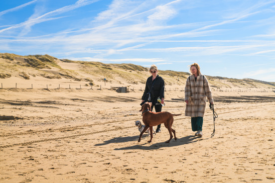 Mensen aan het wandelen op een breed zandstrand in Noord-Holland